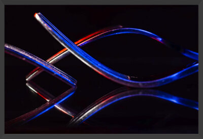 Abstract of three forks and their reflections under blue and red lights.